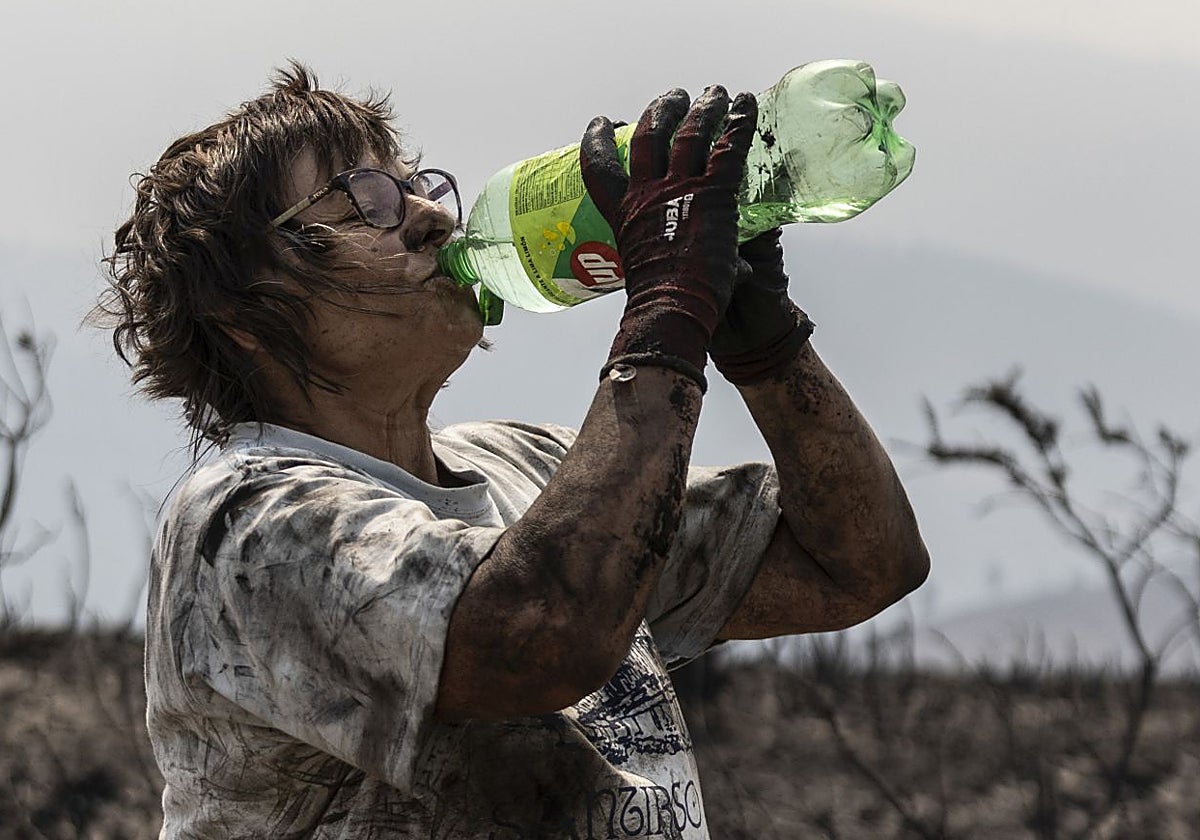 Una vecina de Orense bebe agua tras limpiar los restos de uno de los incendios de este agosto