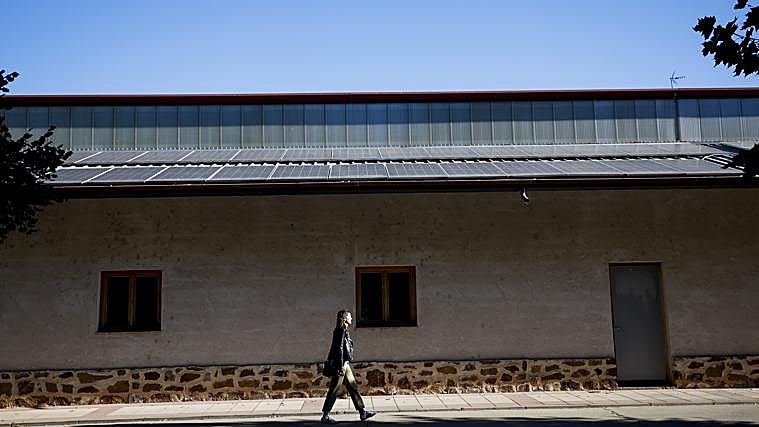 Persona camina junto a placas solares en pueblos de la España Vaciada
