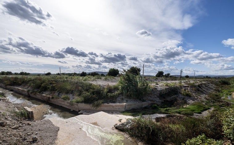 Imagen principal - Su particular orografía hace que el Poyo se estreche aguas abajo, cuando el terreno se hace más llano.. En la imagen superior, el giro de 90 grados que el Poyo hace apenas un kilómetro después de donde se encuentra el caudalímetro. Además del imposible giro para el agua,el cauce es mucho más reducido que aguas arriba. En la segunda foto, las obras de reconstrucción del puente sobre el bypass que derribó el barranco del Gallego. Se puede observar la anchura del barranco en ese punto, cuando unos metros más abajo (en la tercera foto), su desembocadura en el cauce principal del Poyo tiene apenas un mar de metros. Esos estrechamientos provocaron que el 29-O toda los campos y los polígonos alrededor se inundaran.