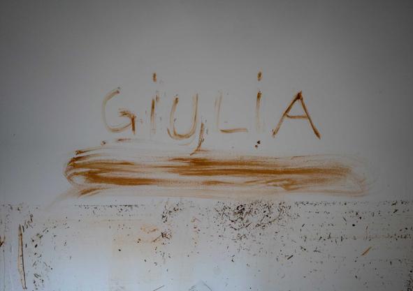 Imagen secundaria 1 - Raquel tenía claro que su hija se llamaría Giulia y, con barro, lo dejó plasmado en la pared de su casa, destrozada. Un año después, el fango ya seco aún cubre los enseres.