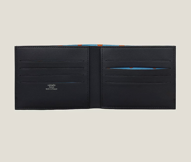 Cartera compacta de Hermès en ternera Swift en azul marino con forro en twill de seda estampado. Precio: 805 euros.
