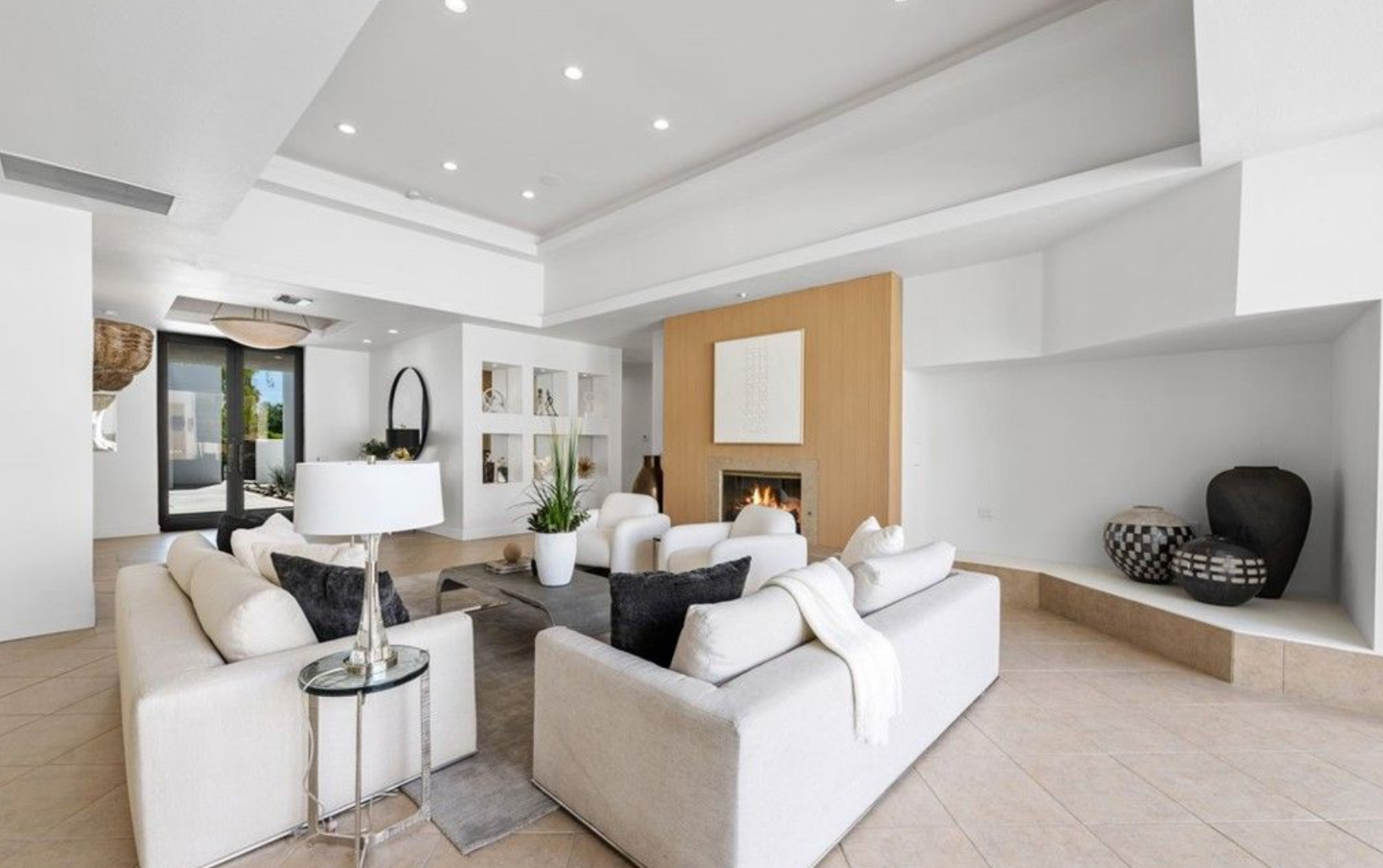 El salón cuenta con chimenea revestida de listones de madera, sofás y acceso directo a la terraza