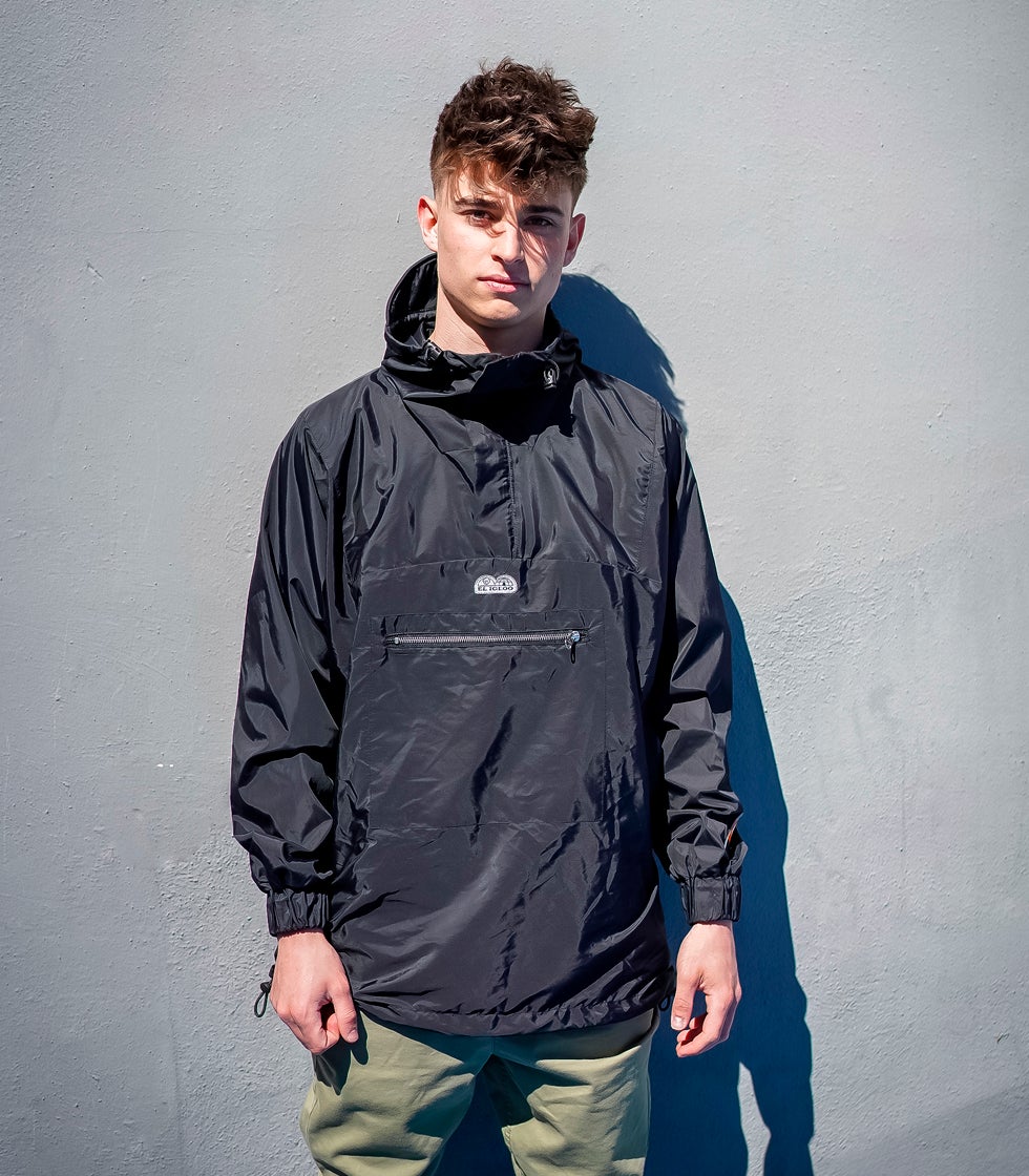 Los cortavientos son básicos en la montaña pero también funcionan fuera de ella. Este de la firma española Pedro Gómez tipo canguro en tejido verona de color negro tiene cremallera central con diente plateado, corchetes en los bolsillos, tanka con cordón elástico y capucha con visera. Precio: 180 euros.