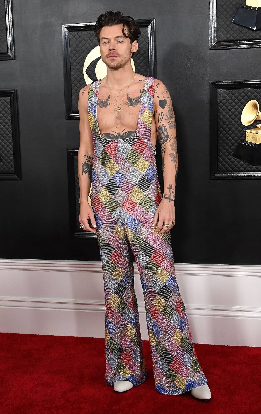 Cerramos esta selección con el triplete fashion de Harry Styles. El artista lleva mucho tiempo derribando estereotipos en la moda y en la gala de los Grammy volvió a hacerlo. Y no solo una sino tres veces en una misma noche, porque debemos hablar del multicolor mono de arlequín con el que pisó la alfombra roja.