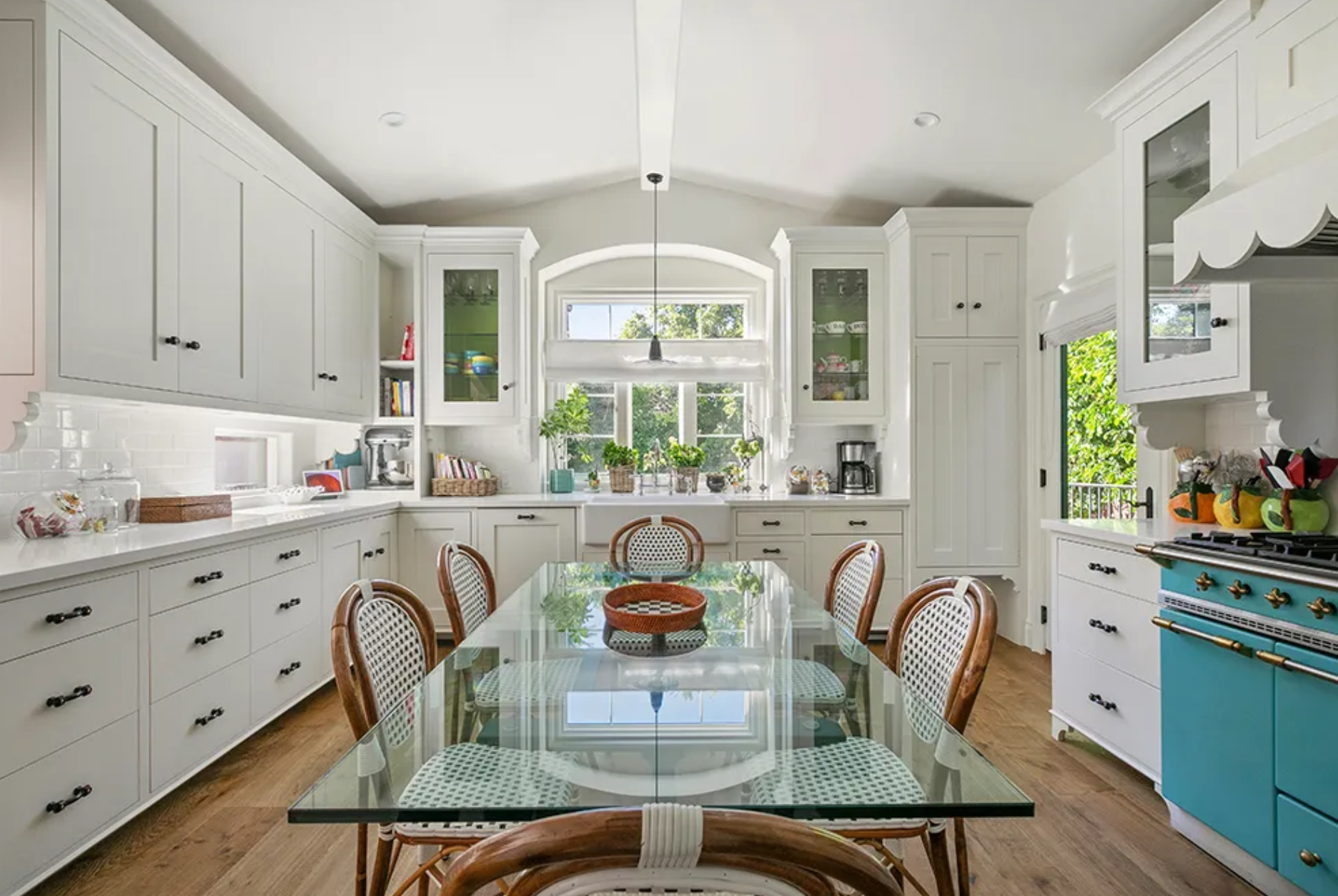 La cocina cuenta con gabinetes de color blanco, electrodomésticos de alta gama y una mesa de cristal con capacidad para seis comensales