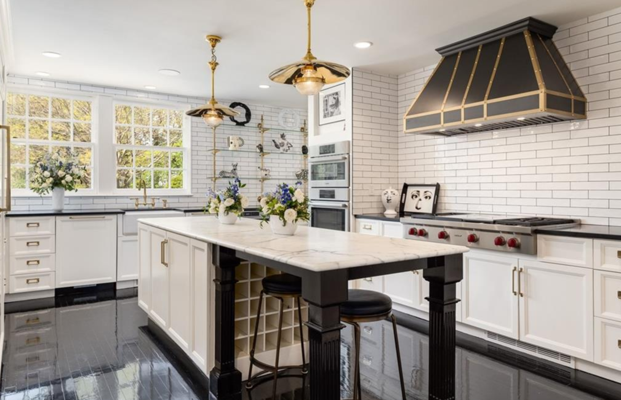 La cocina cuenta con gabinetes blancos, electrodomésticos de alta gama de acero inoxidable y una isla central con zona de desayuno