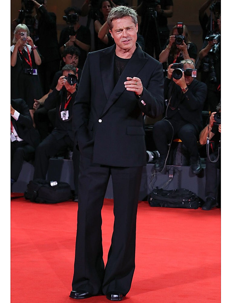 Brad Pitt con un traje negro,con pantalones campana y blazer cruzada en la alfombra roja del Festival de Venecia.
