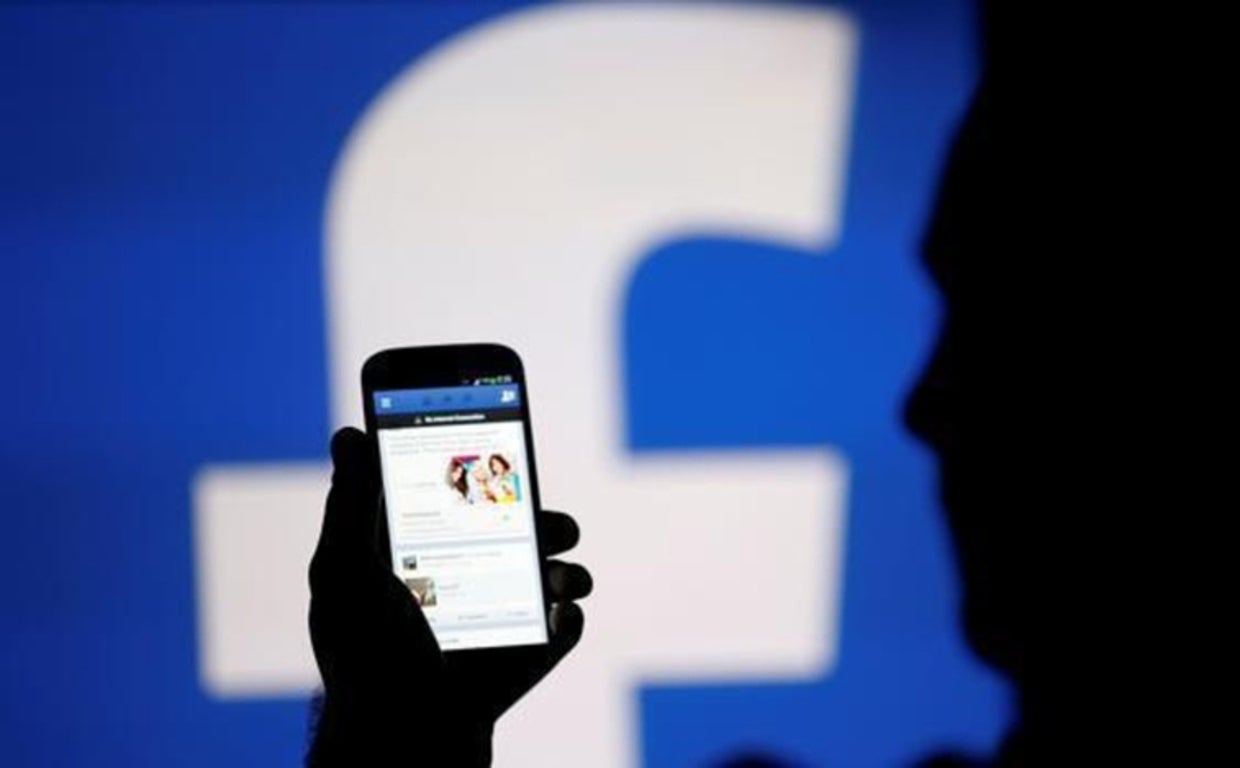 Fotografía de archivo de una persona utilizando Facebook desde su teléfono móvil