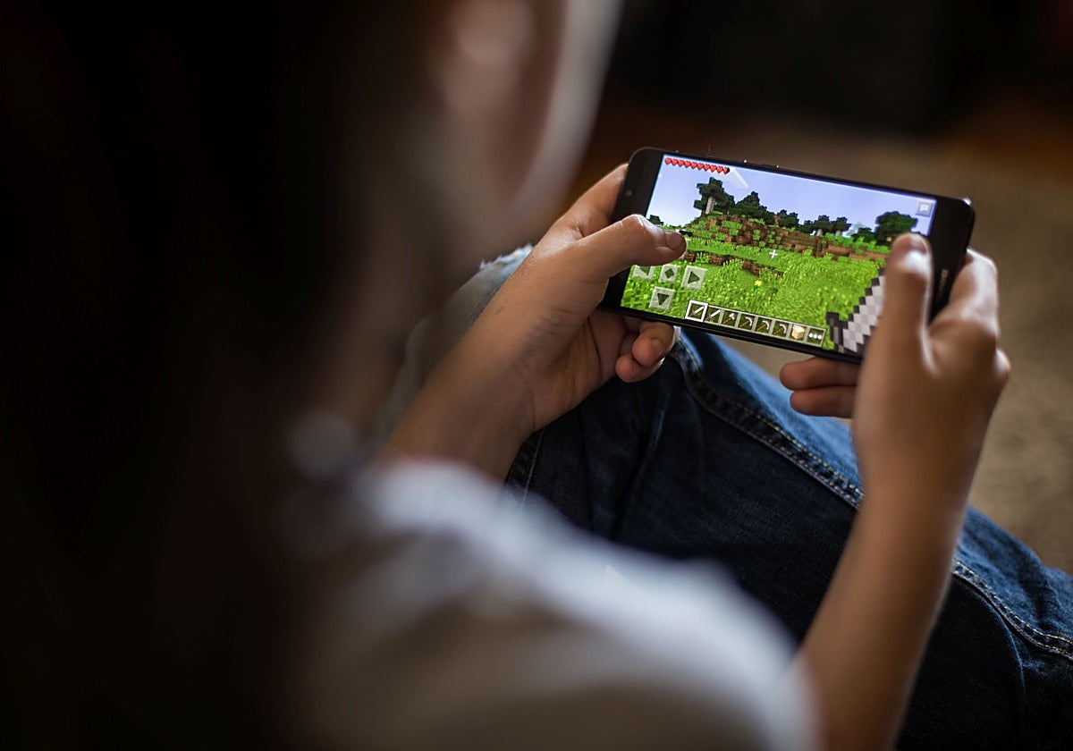 Una niña juega al Minecraft en su móvil