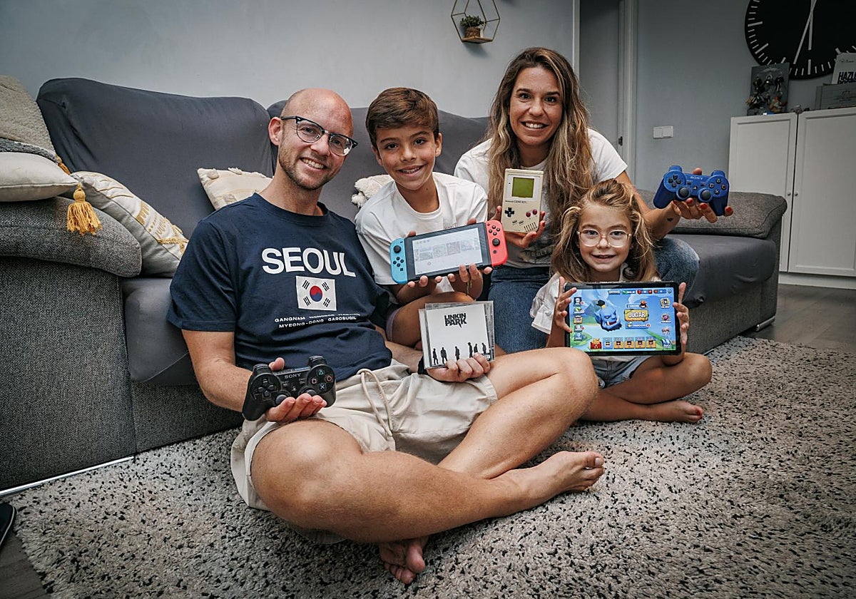 Ester y Diego muestran sus dispositivos de la infancia acompañados por sus hijos, Celia y Lucas, que enseñan su tableta y su Nintendo Switch