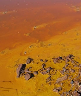 Imagen secundaria 2 - El agua del río Tinto tiene un pH bajo, muy ácido, con alto contenido en metales pesados, lo que no impide que vivan microorganismos. Los científicos estudian aquí las similitudes con con la vida en Marte. A la izquierda, la locomotora de vapor número 14, construida en 1875 en Manchester, la más antigua de España en funcionamiento. Arriba, galería y mirador de Mina Peña de Hierro