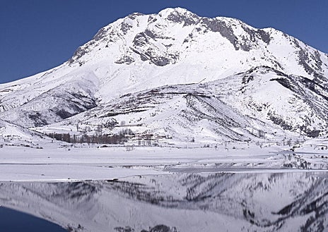 Imagen secundaria 1 - Arriba, la cavidad inicial de la Cueva del Cobre por la que aflora el río Pisuerga. Sobre estas líneas, a la izquierda, el Pico Espigüete (2450 m) reflejado sobre el embalse de Camporredondo. A la derecha, el claustro del monasterio de Santa María la Real, en Aguilar de Campoo