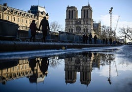 Los peatones pasan por enter barreras de seguridad y vallas colocadas alrededor de la catedral de Notre-Dame el 6 de diciembre, un poco antes de la reapertura oficial