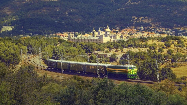 Tren de Felipe II viajando por la vía con San Lorenzo de El Escorial al fondo