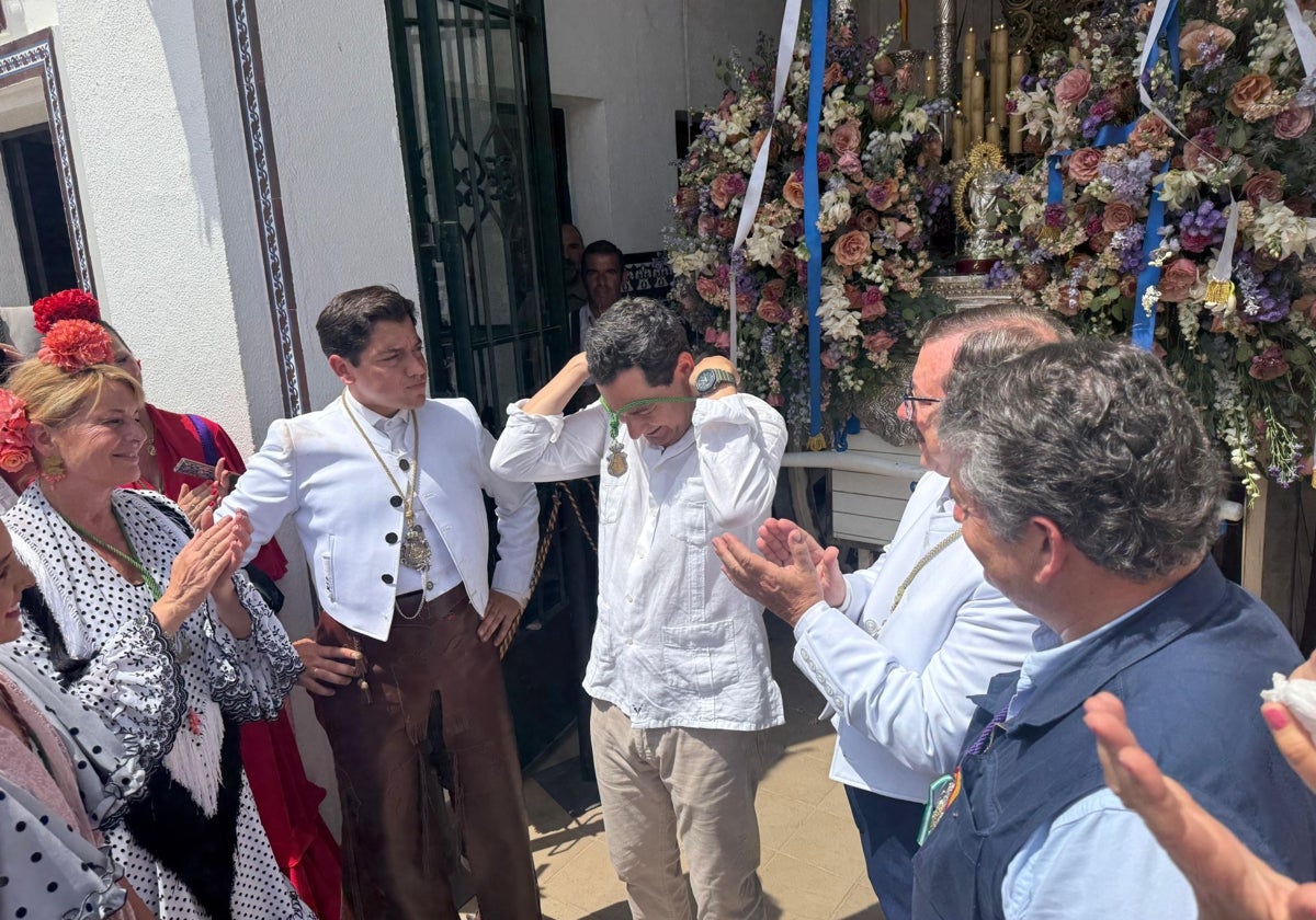Juanma Moreno colocándose la medalla de la Hermandad de Huelva