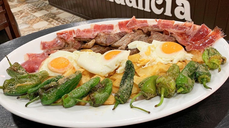 Plato de huevos fritos con patatas, pimiento, jamón y lomo servido en la Abacería La Abundancia