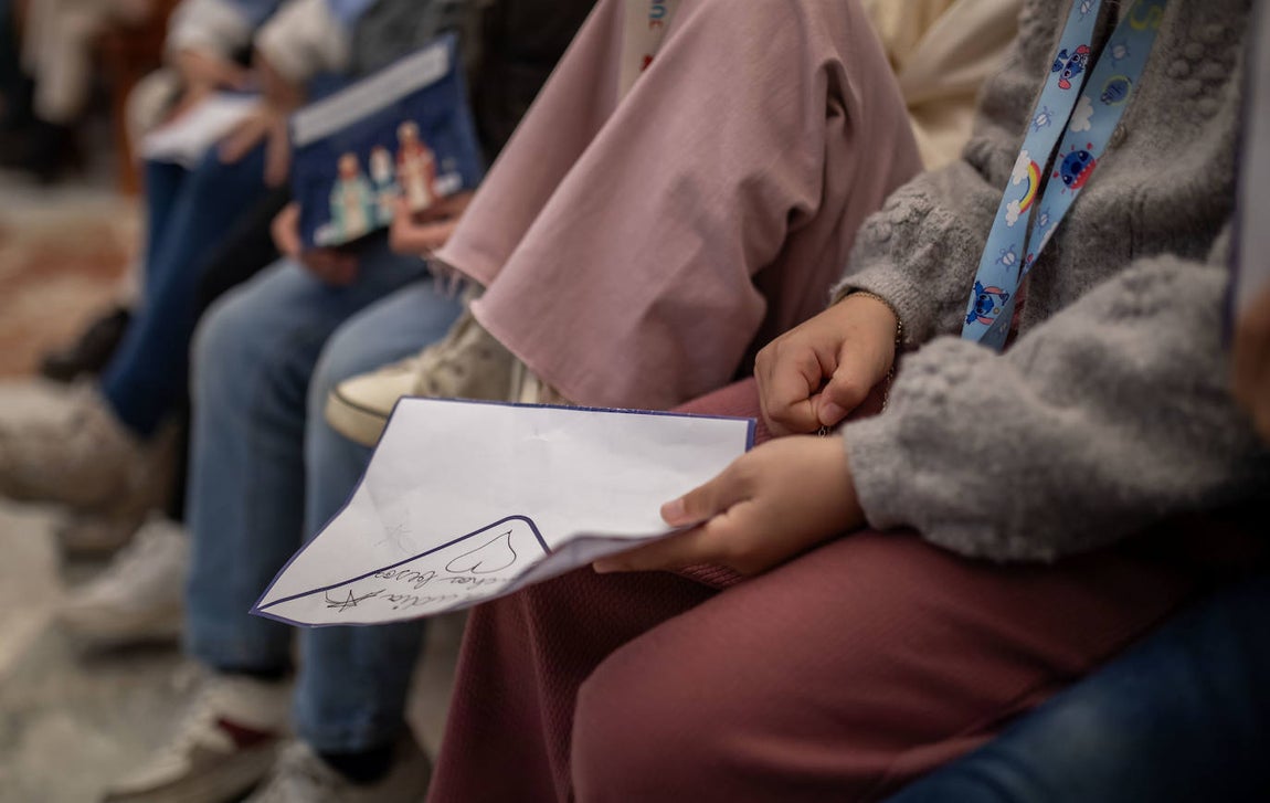 Niños aguardan al Heraldo Real con sus cartas en la mano