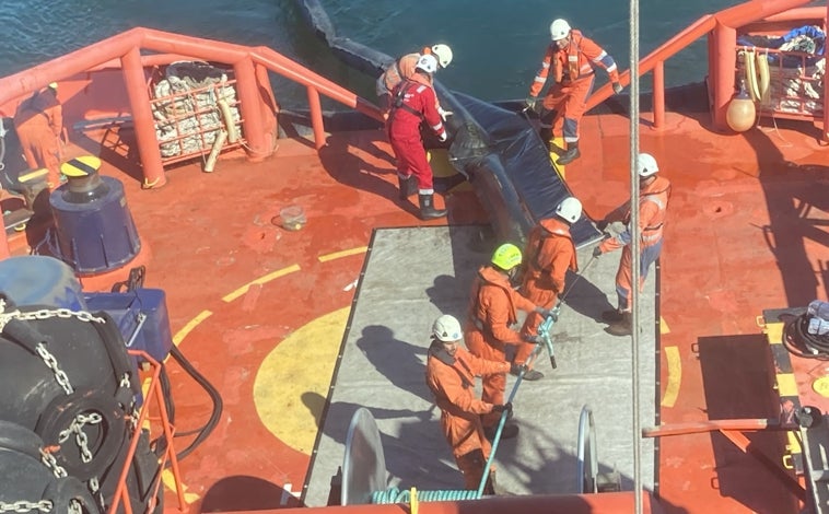 Imagen principal - Momento en el que se empieza a recoger la barrera oceánica, la rasera siendo bajada al agua y el tanque portátil