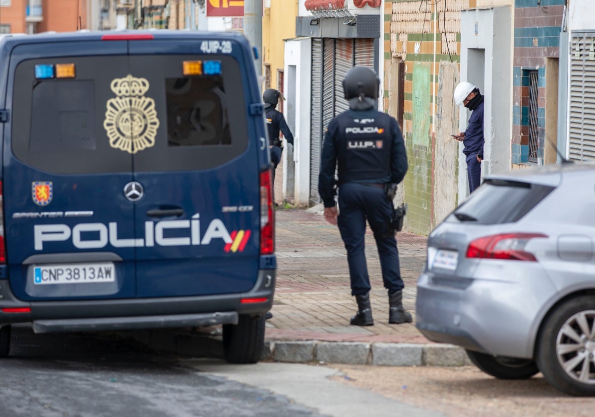 Un técnico sale de la vivienda donde acaba de intervenir mientras le custodia la Policía