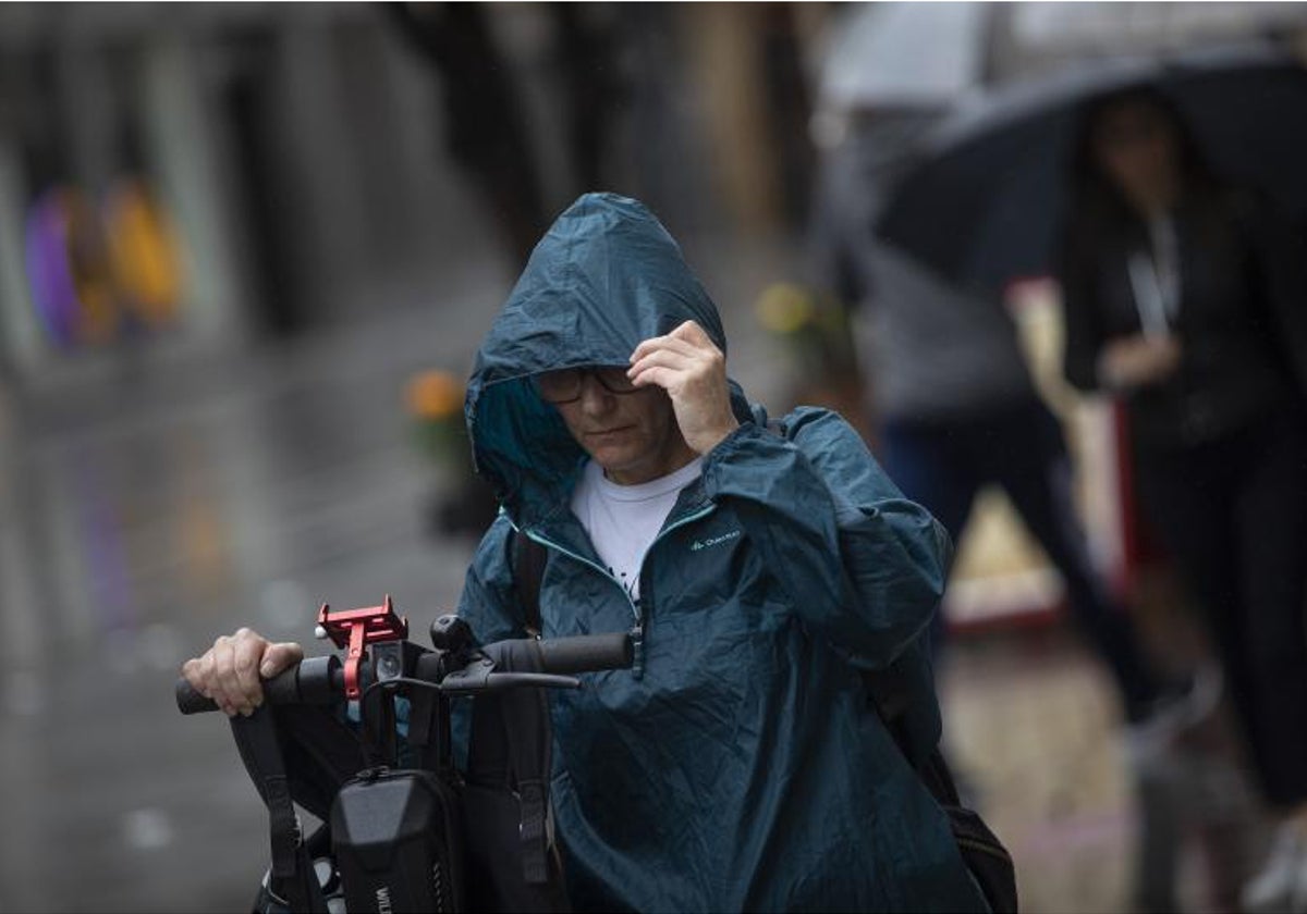 Una mujer se protege de la lluvia con un chubasquero