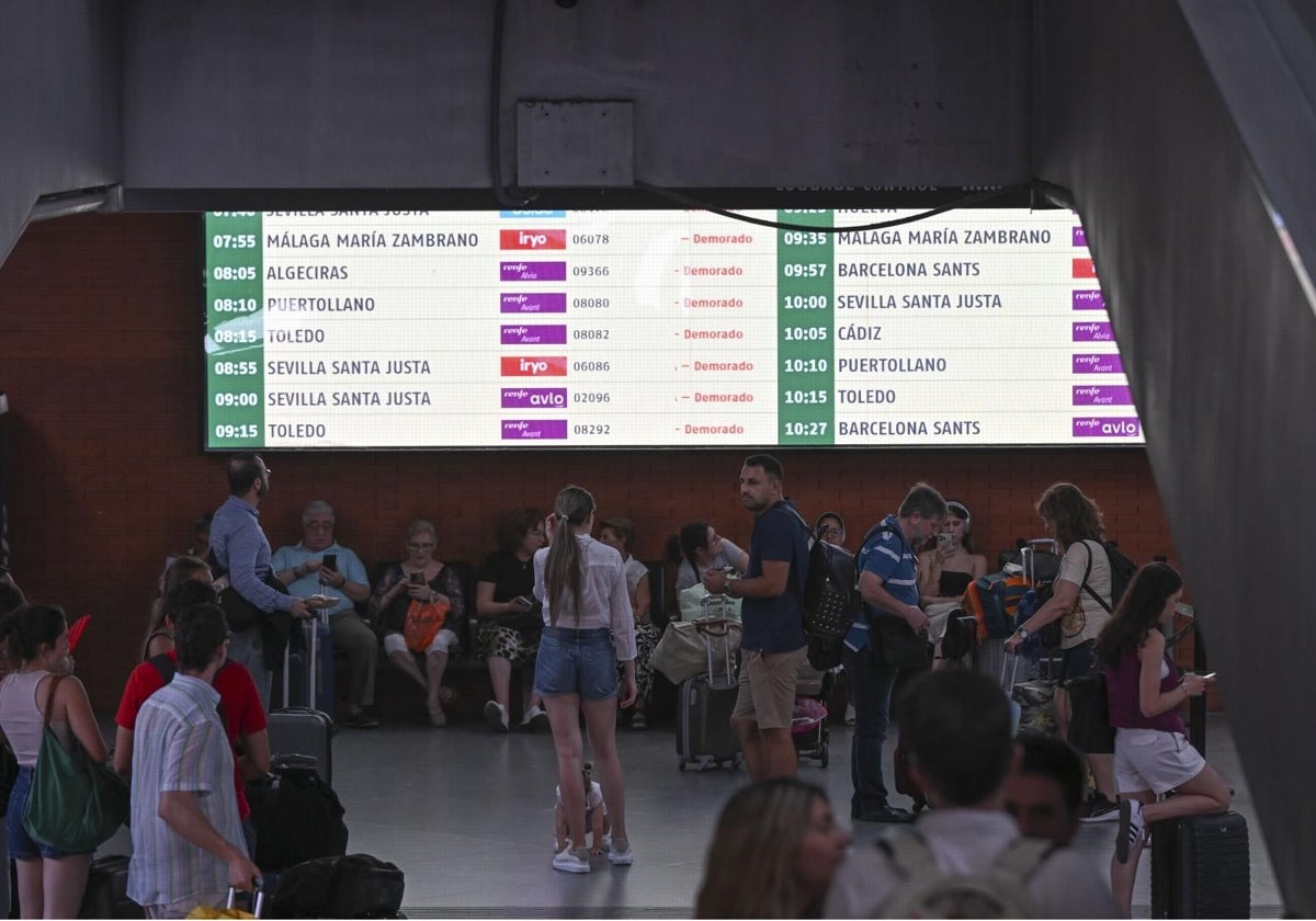 Pasajeros ante una pantalla que informa de los trenes demorados