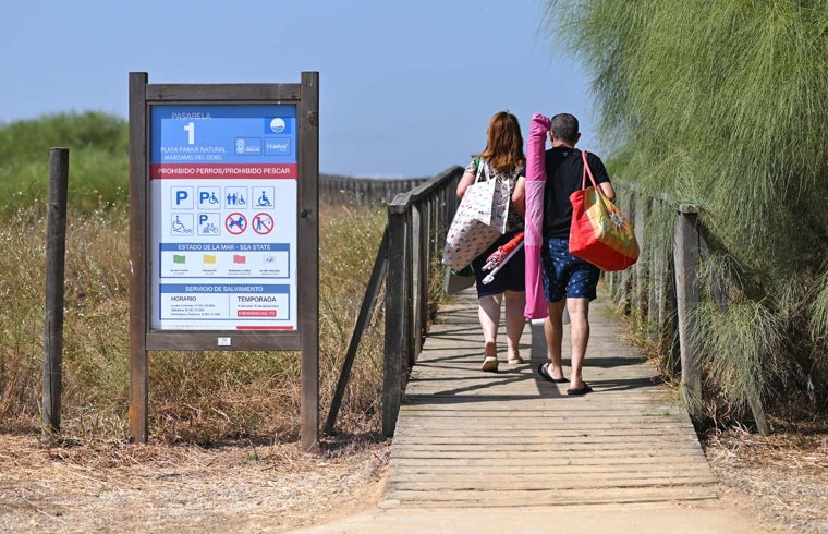 Una pareja accede a la pasarela que conduce a la playa