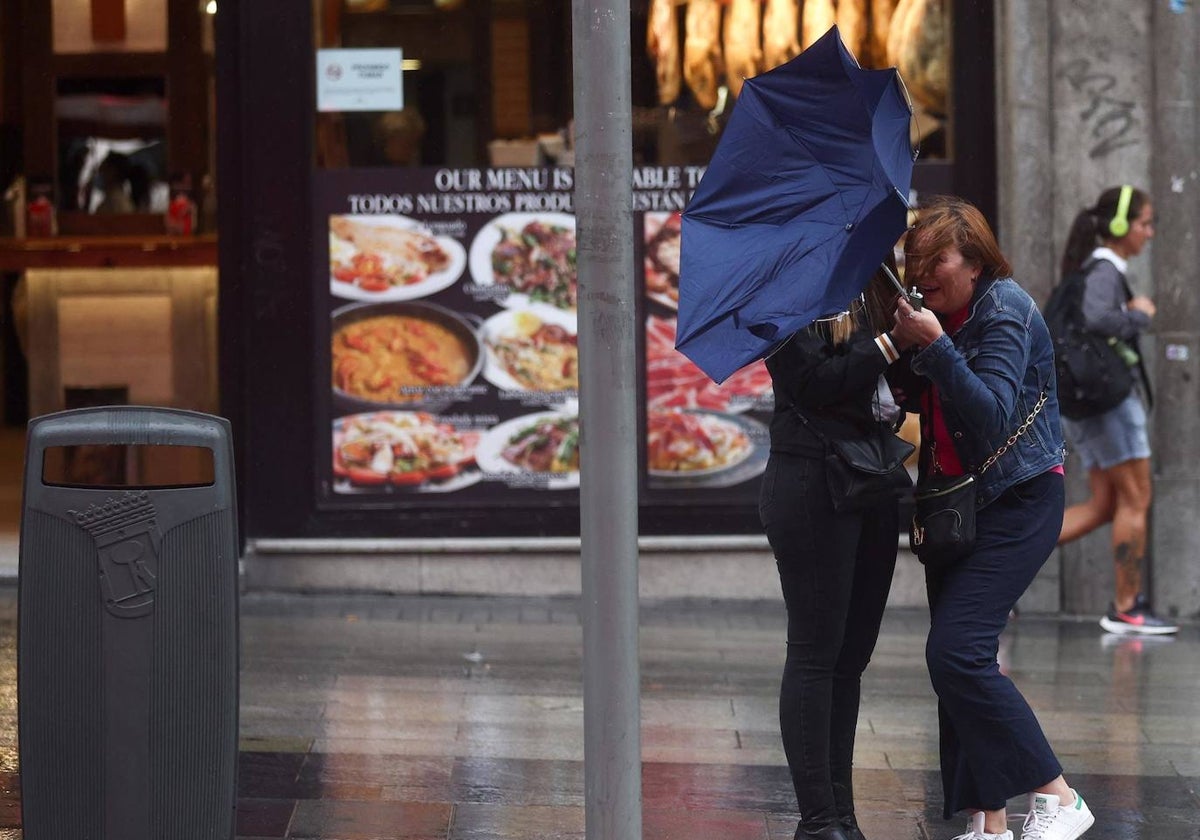 Dos personas tratando de resguardarse bajo la lluvia