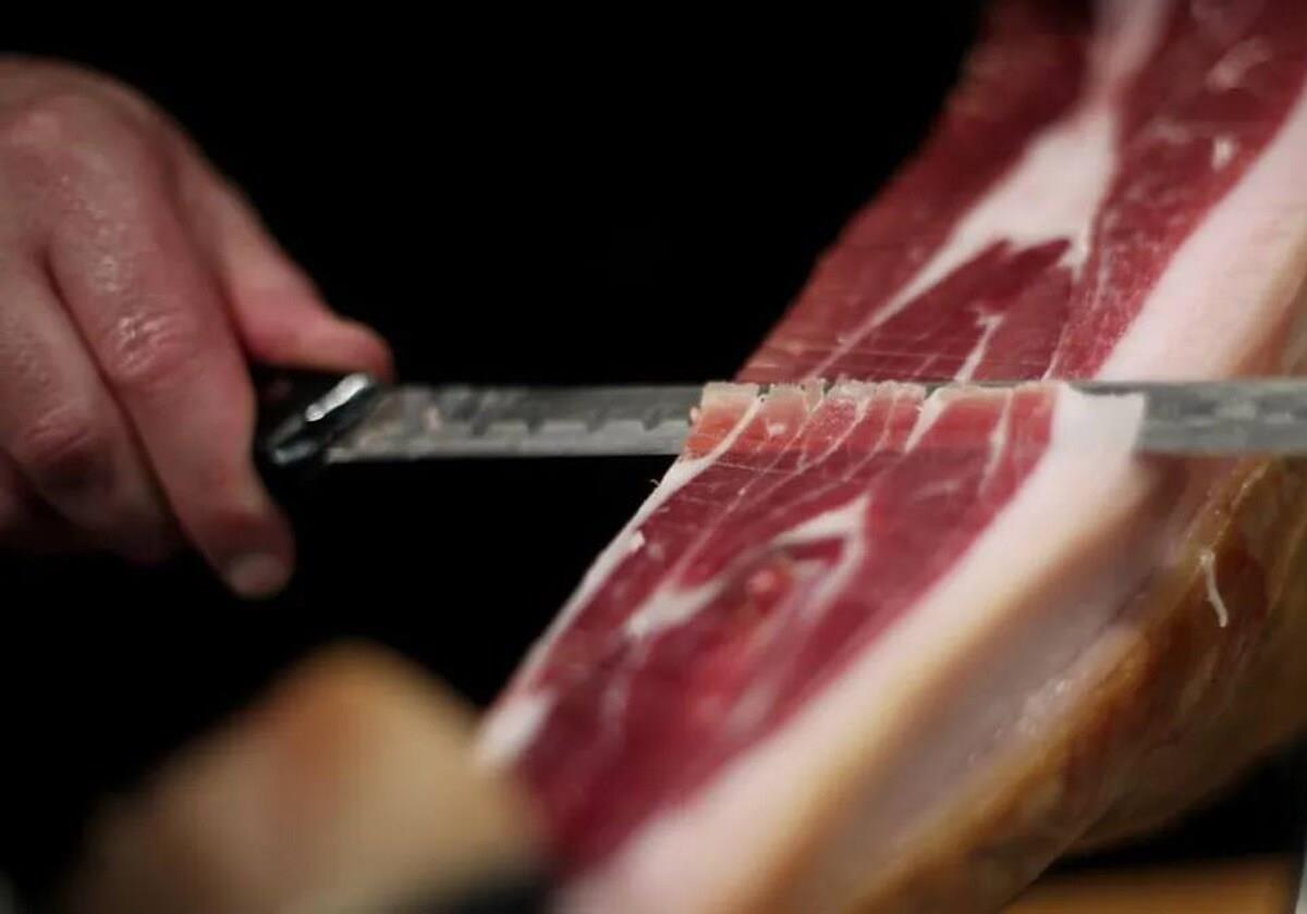 Un cortador de jamón cortando una loncha