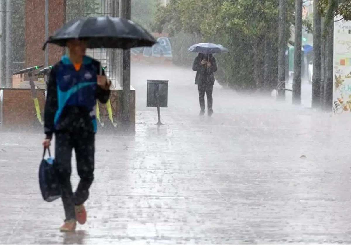 Dos personas se protegen de una aguacero