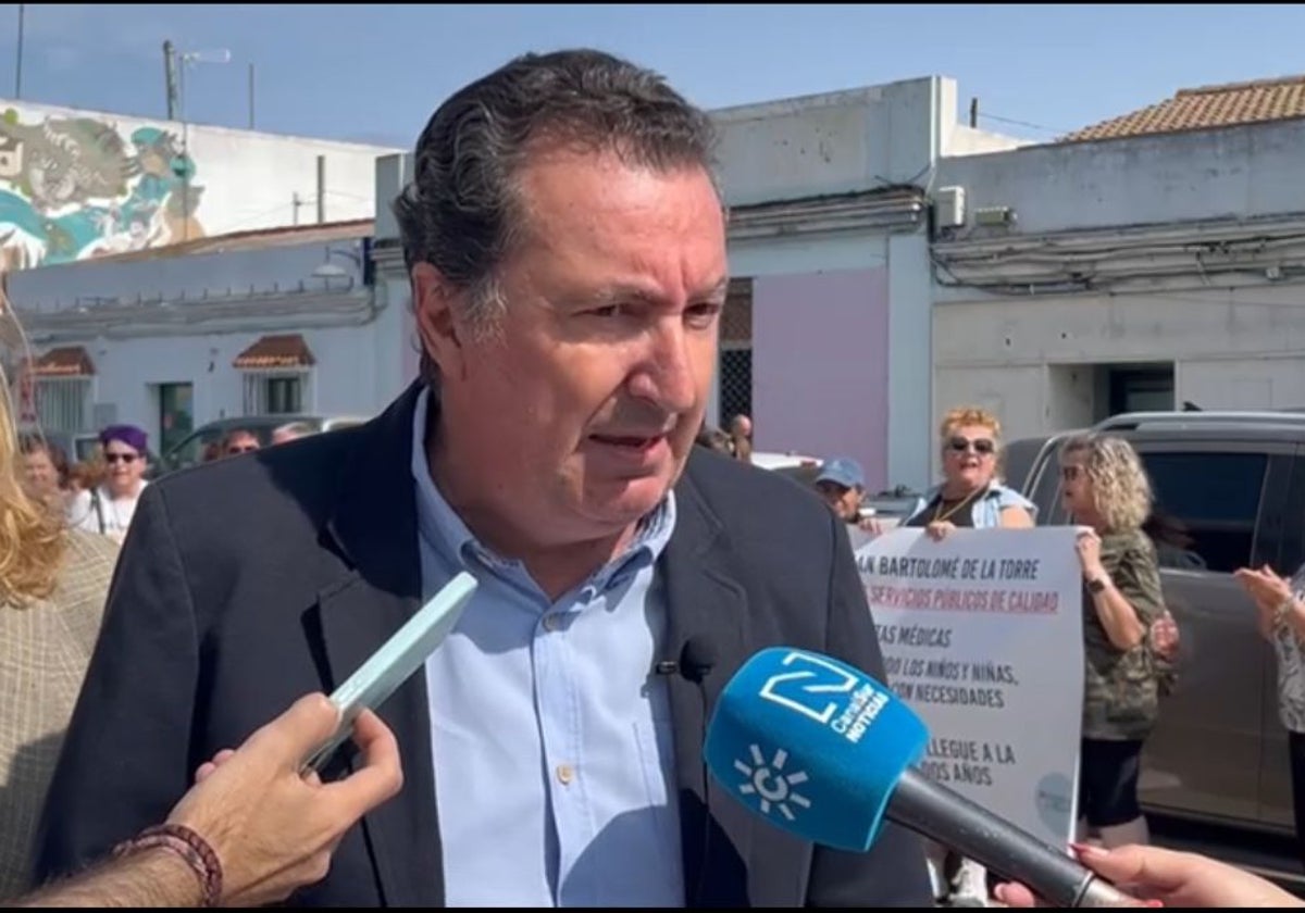 El presidente del PP de Huelva y detrás los manifestantes