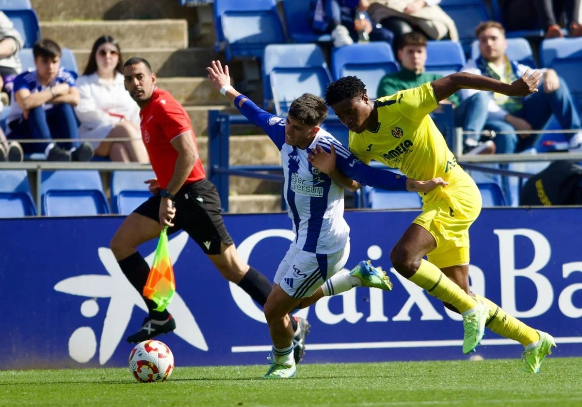 Paolo Romero exigido por un rival durante el Recreativo-Villarreal B en el Nuevo Colombino