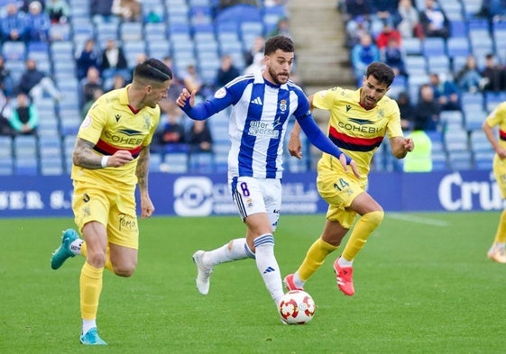 Luis Alcalde avanzando con el balón ante dos adversarios del Atlético Sanluqueño