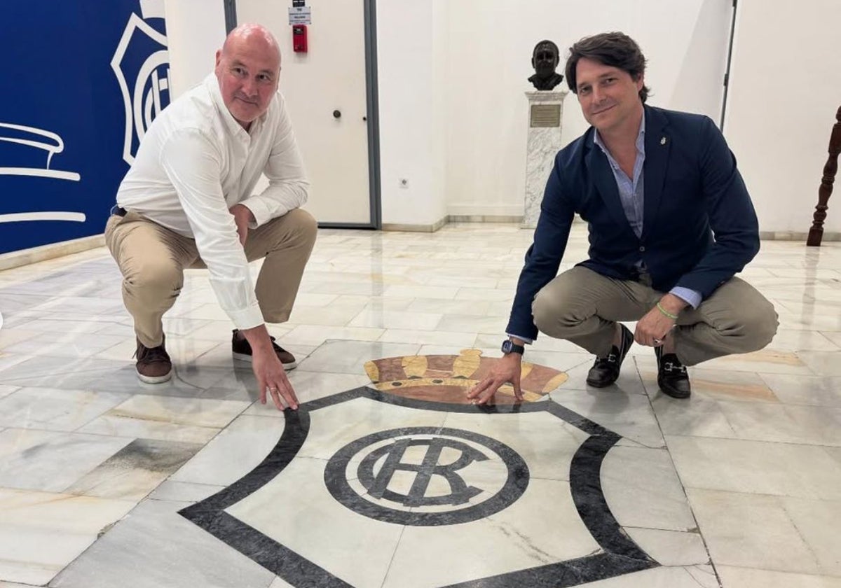 Roberto Ríos y Adrián Fernández, junto al escudo del Decano