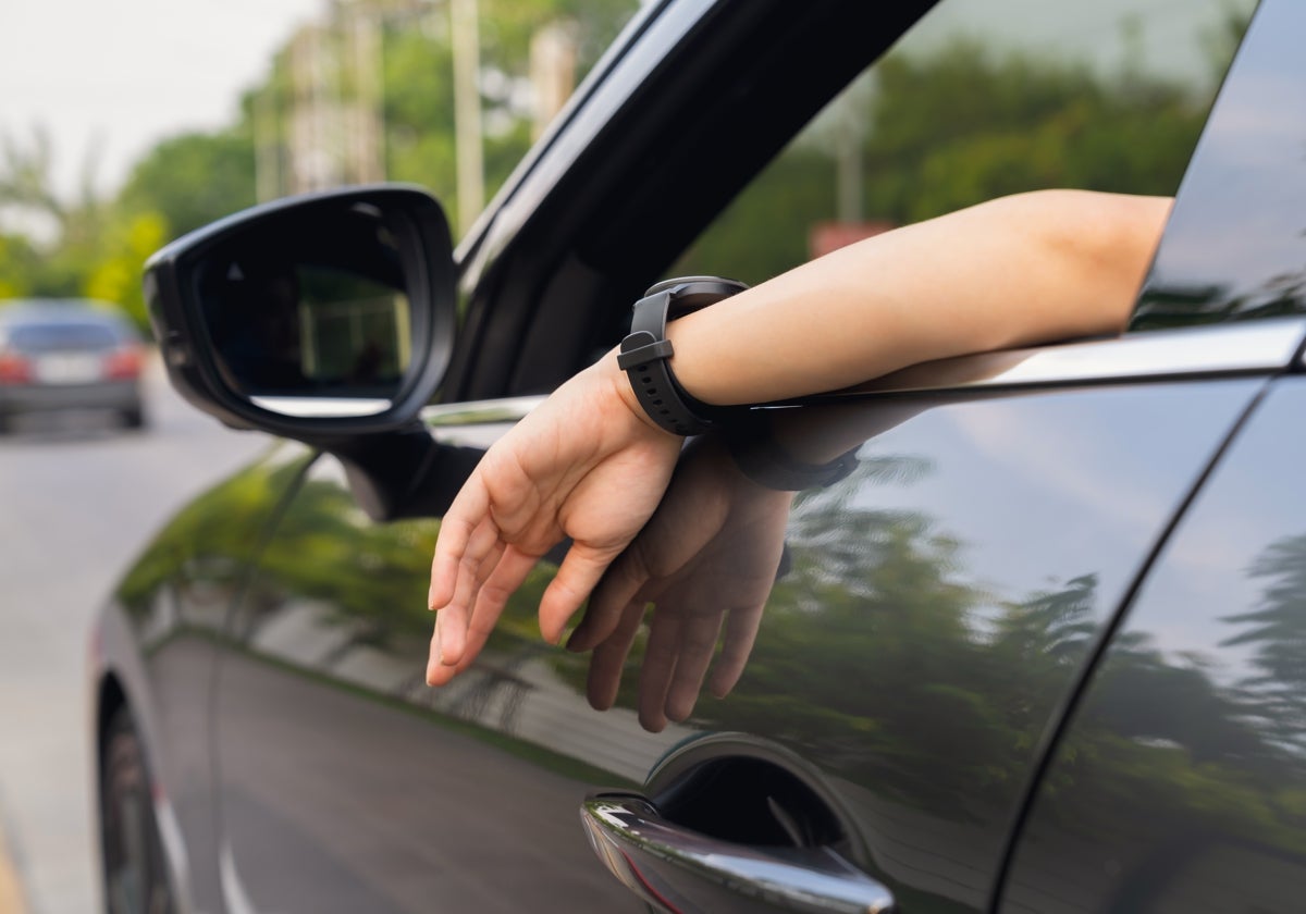 Un hombre sacando el brazo por la ventanilla de un coche