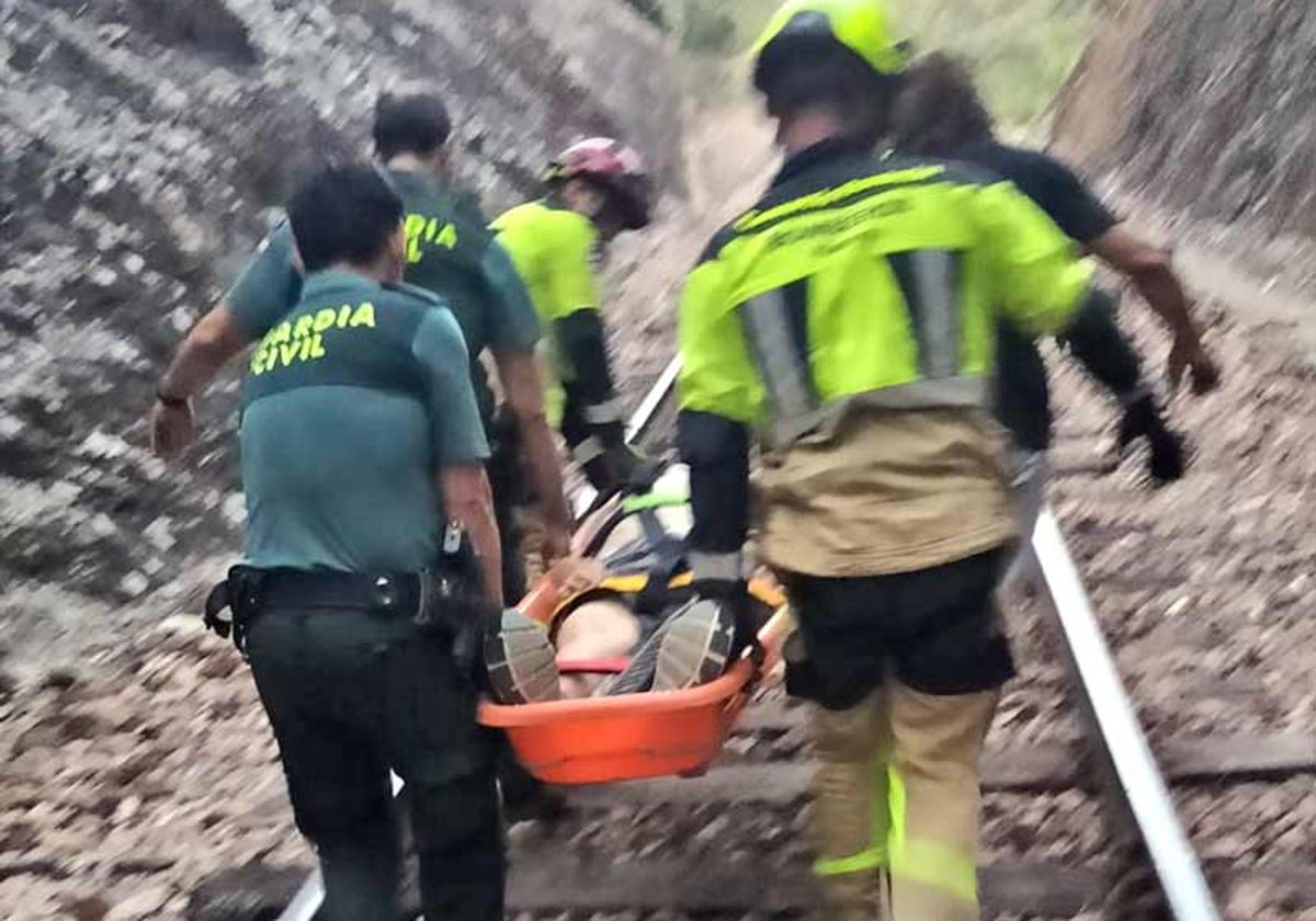 Bomberos y guardias civiles llevan al herido a una zona donde pueda ser atendido por los servicios sanitarios