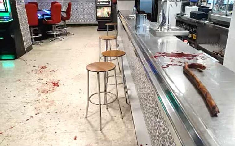 Imagen principal - Arriba, La garrota usada en la pelea sobre el mostrador del salón de juegos. Sobre estas líneas, la policía atiende al herido y a la derecha el interior del local, donde se inició la reyerta