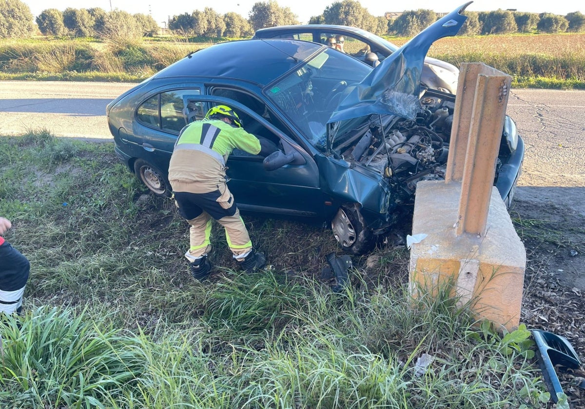 Bombero junto al coche siniestrado en el término municipal de Niebla