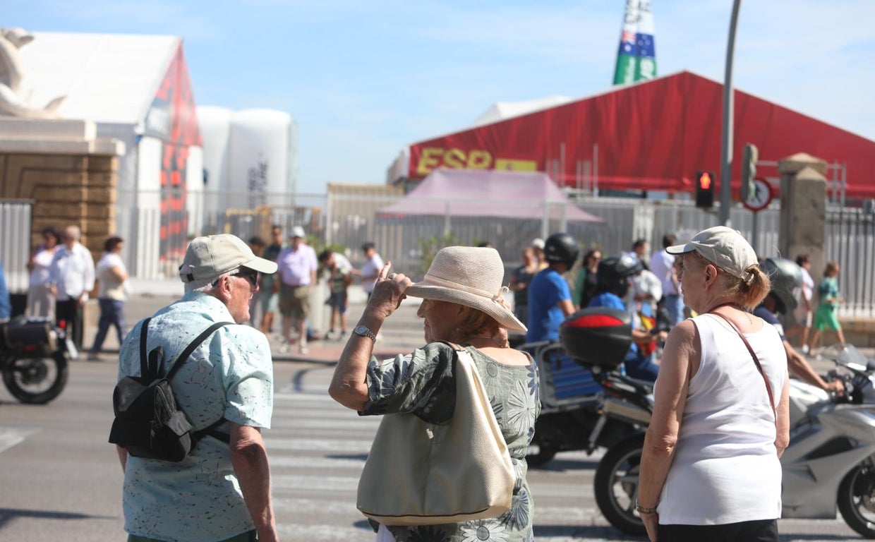 El público, a cubierto del sol, cruza la Avenida del Puerto llena de motos a mediodía de este sábado.