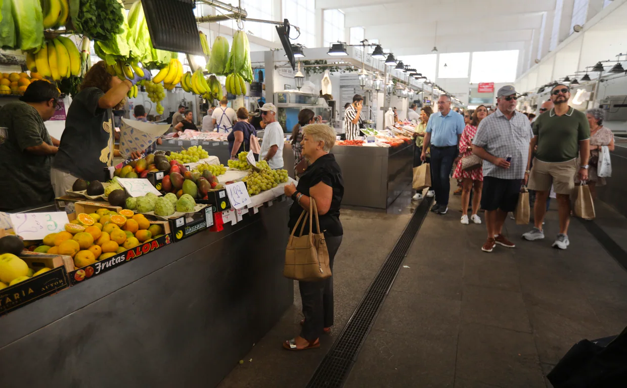 Una mujer compra en una frutería en el mercado de abastos de Cádiz