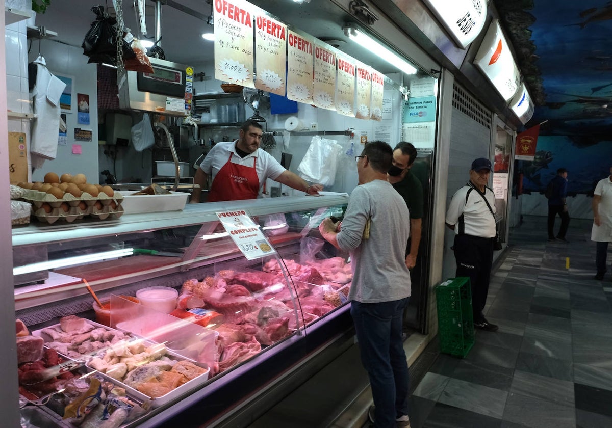 Un cliente conserva con un carnicero en el gaditano mercado de la Virgen del Rosario.