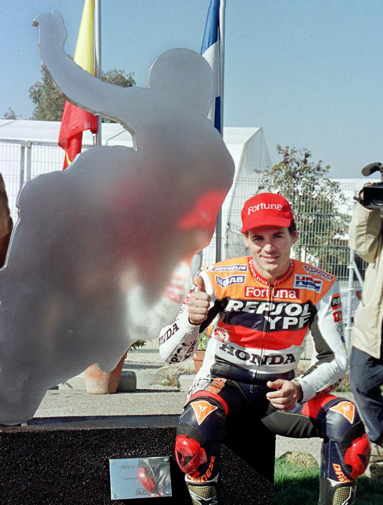 El piloto español, actual campeón del mundo de 500 cc, Alex Crivillé posa  junto a una reproducción de su silueta que da  nombre a una curva del Circuito de Jerez.