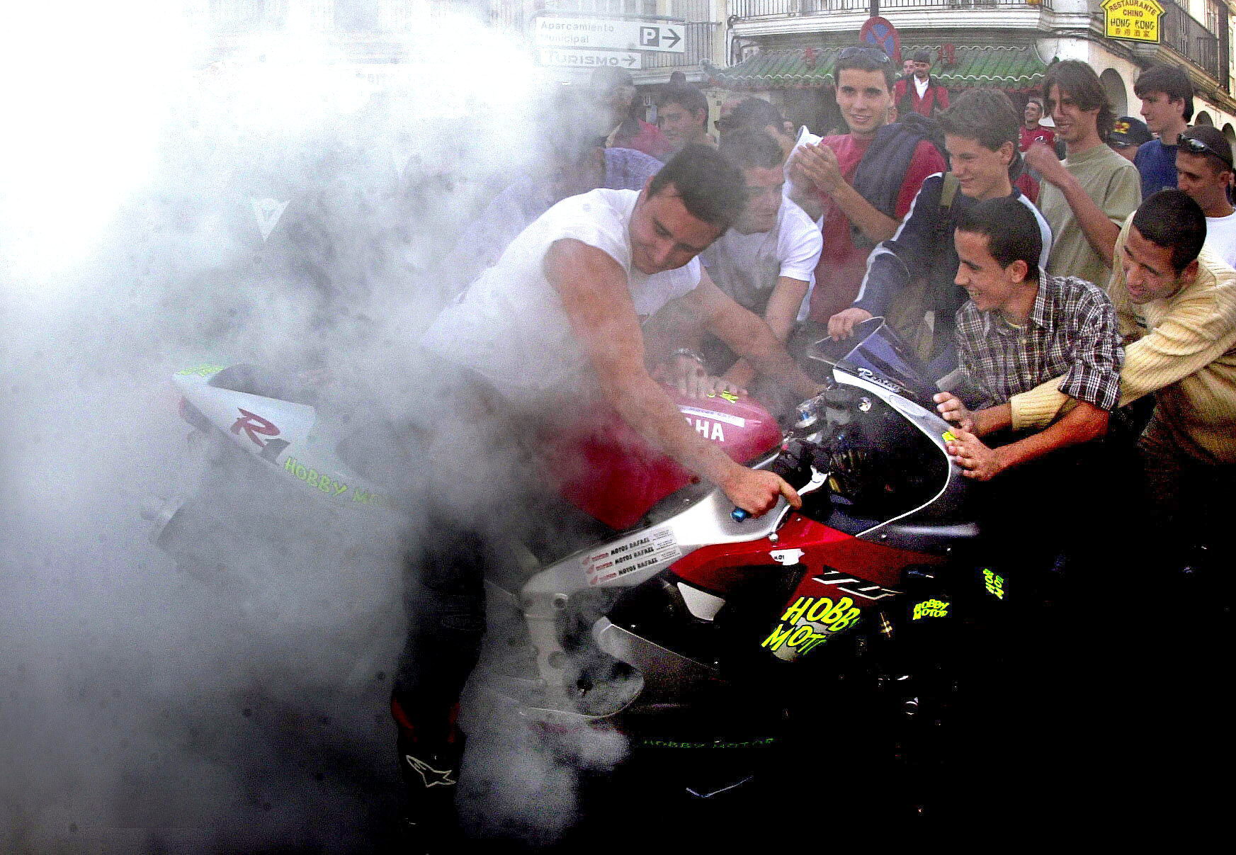 Un motorista levanta su moto en una céntrica calle de Jerez participando en el ambiente del Gran Premio de Motociclismo.