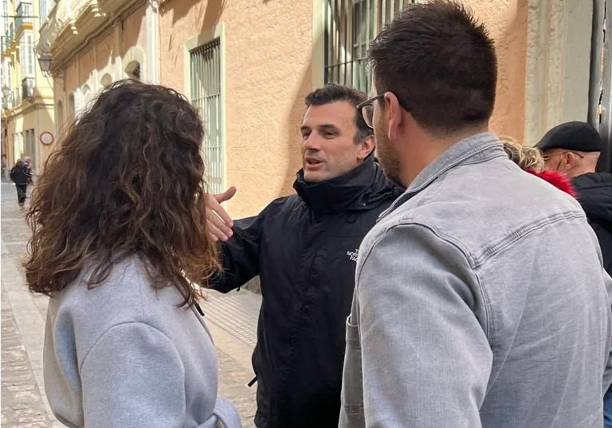 El candidato del PP, Bruno García, habla con varios jóvenes en las calles de Cádiz.
