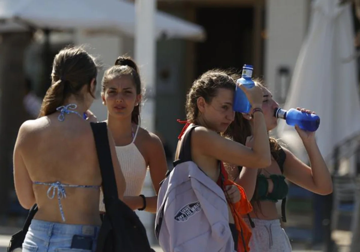 Varias jóvenes beben agua para combatir la ola de calor.