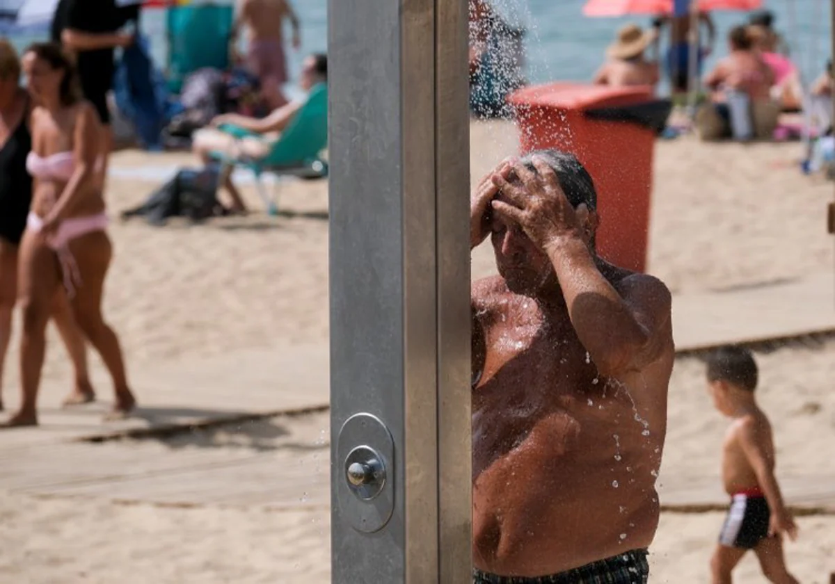 Un hombre, duchándose en una playa de la capital