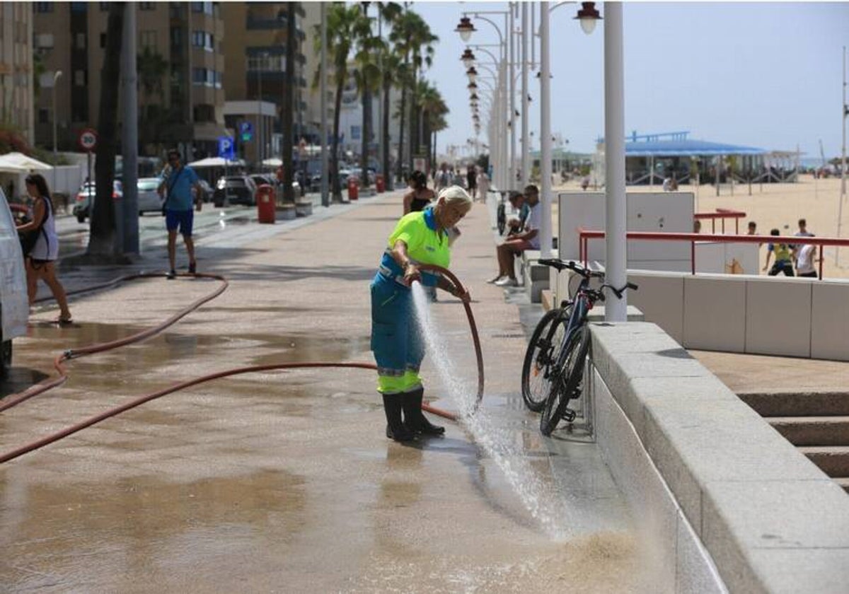 Una trabajadora baldea el Paseo Marítimo durante el plan de choque de limpieza