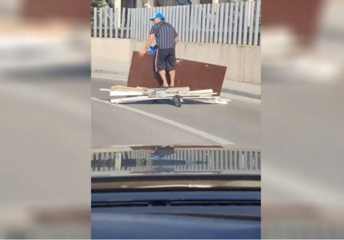 El hombre, cargado de materiales en su patinete eléctrico