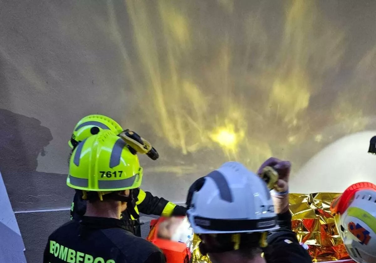 Bomberos y sanitarios actuando en la vivienda y socorriendo a la mujer