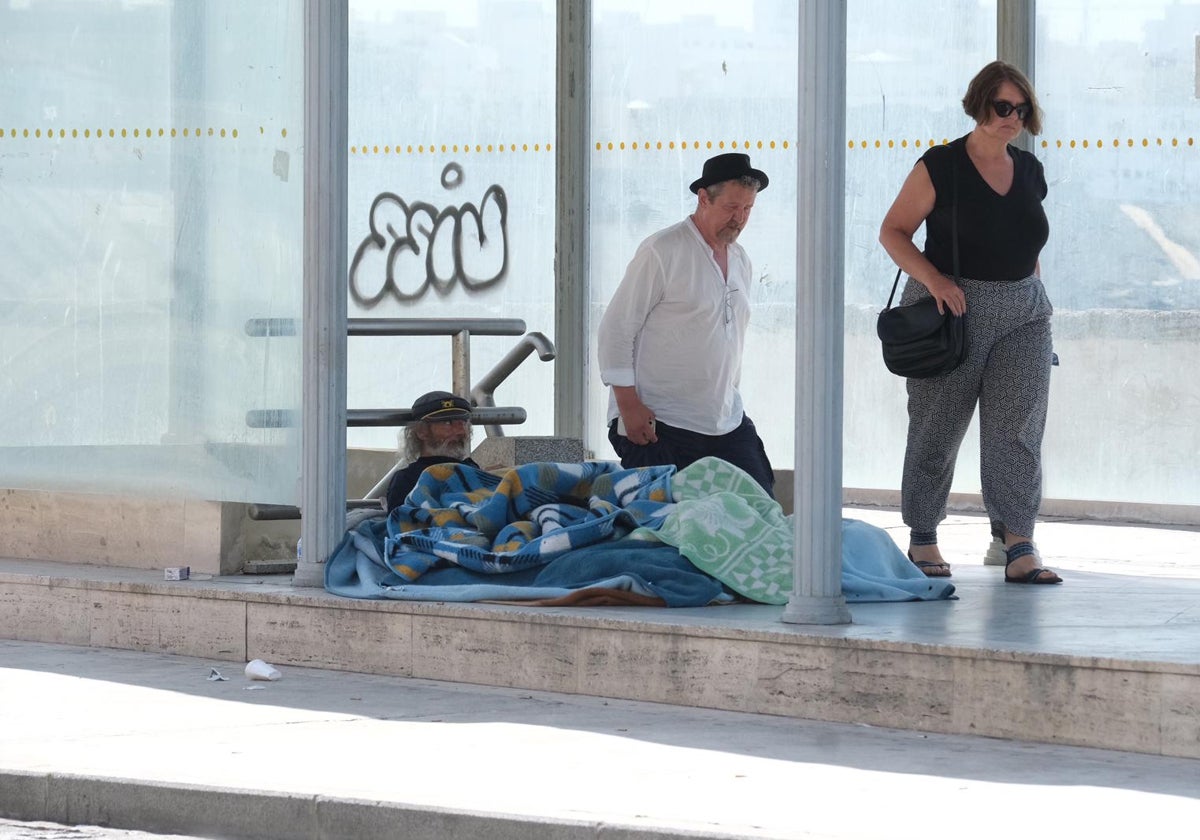 Dos personas pasan por delante de un indigente en la capital gaditana