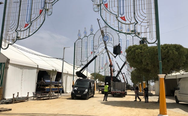 Operarios ultiman la iluminación de las calles de la feria.